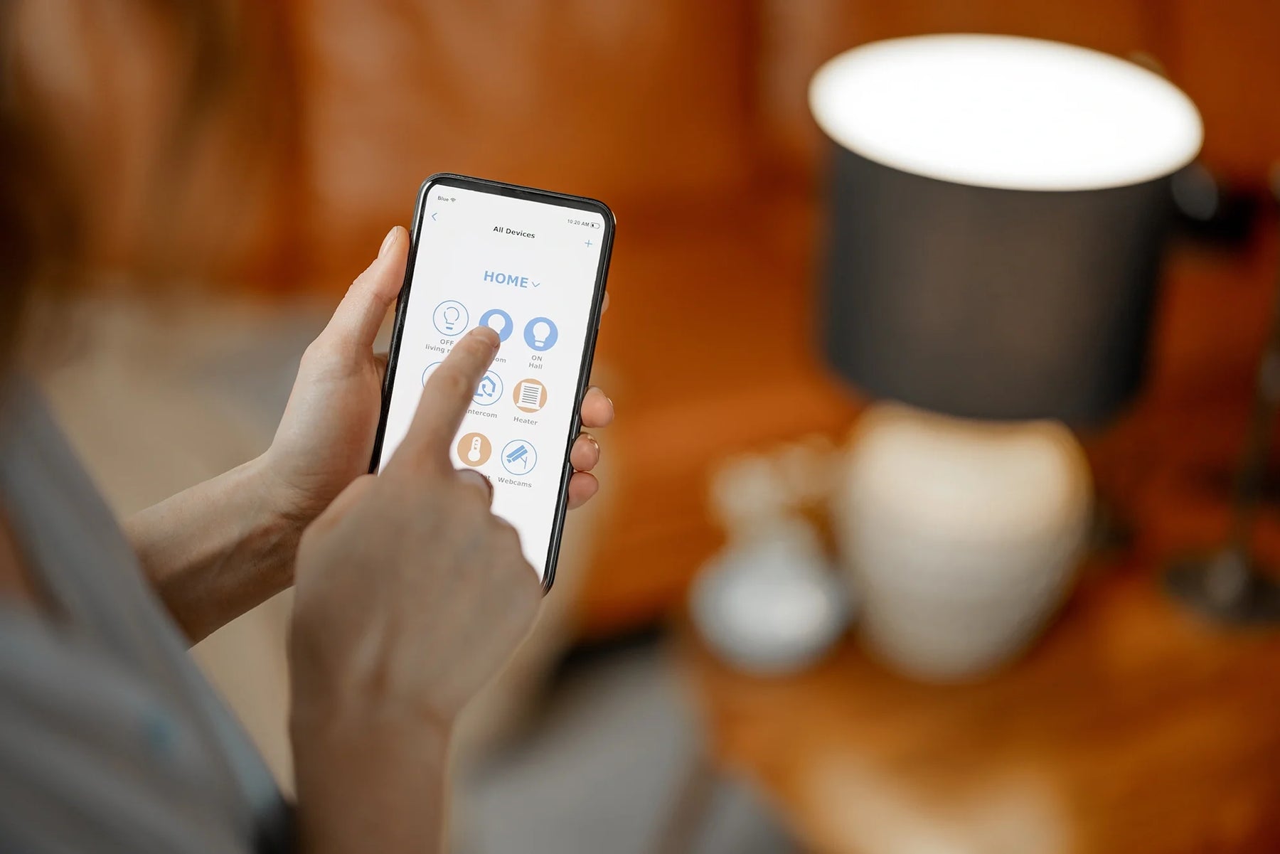 Persona che regola l'illuminazione domestica intelligente tramite app da smartphone in un ambiente domestico