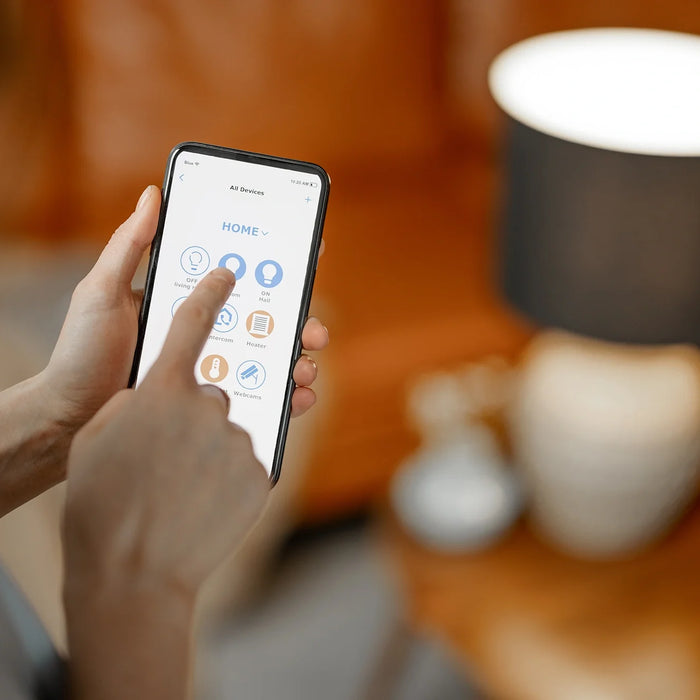 Persona che regola l'illuminazione domestica intelligente tramite app da smartphone in un ambiente domestico