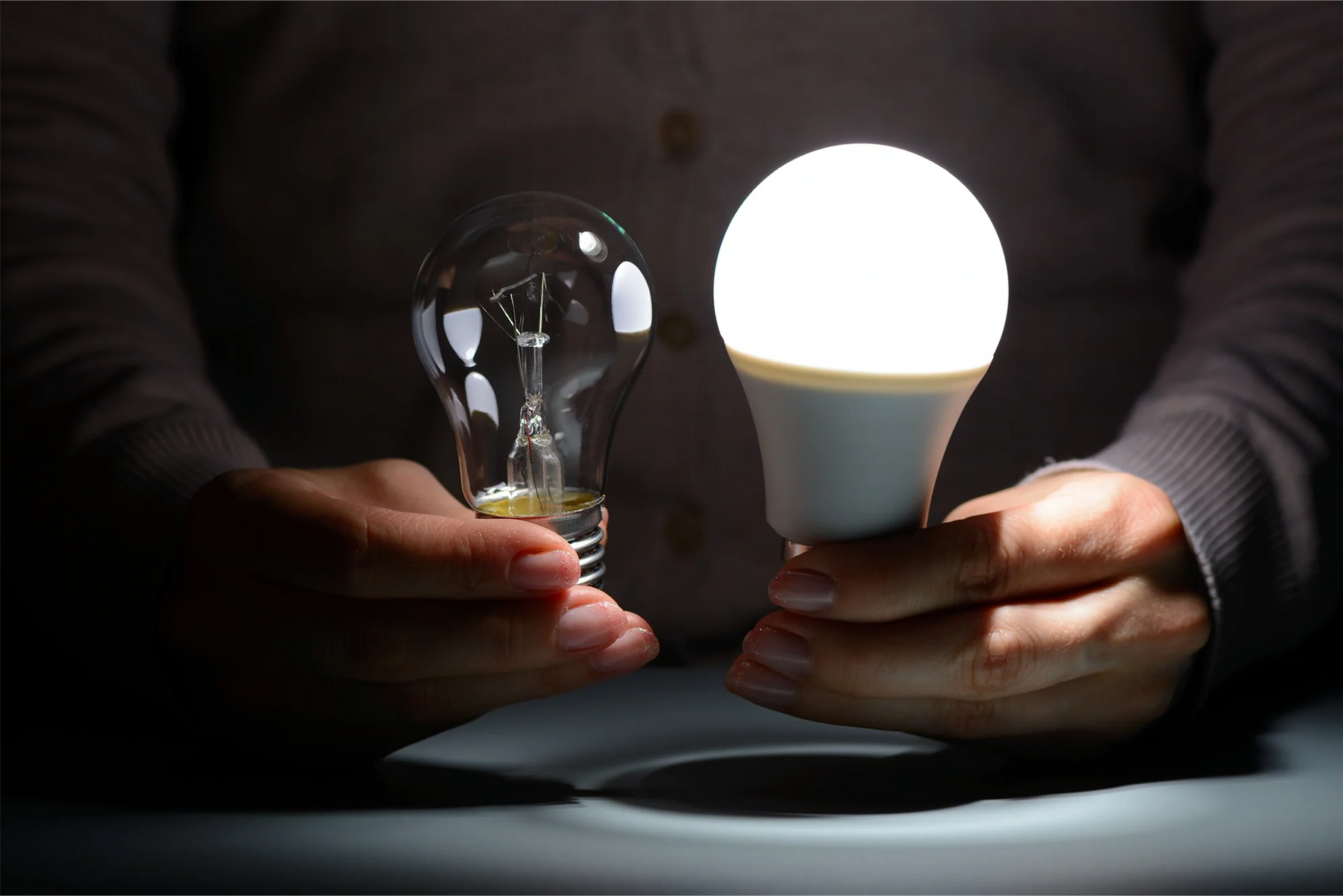 Persona che sostituisce una lampadina tradizionale con una lampadina LED a risparmio energetico