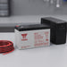 Batteria al piombo sigillata Yuasa NP7-12 12V 7Ah, accanto a un gruppo di continuità